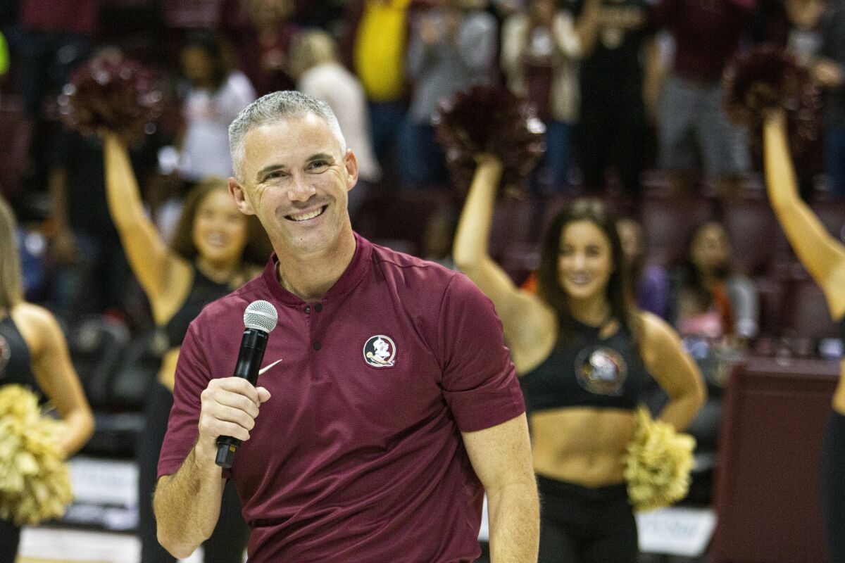 FILE - Florida State's new head football coach Mike Norvell smiles after being introduced during half-time of an NCAA college basketball game against Clemson in Tallahassee, Fla., Sunday, Dec. 8, 2019. Norvell’s first season at Florida State should be an upgrade from the Willie Taggart era. Taggart's tenure was one of college football’s biggest coaching debacles in recent years. He posted four winning seasons at Memphis before taking over in Florida’s capital. He's now tasked with getting the Seminoles back to national prominence. (AP Photo/Mark Wallheiser, File)