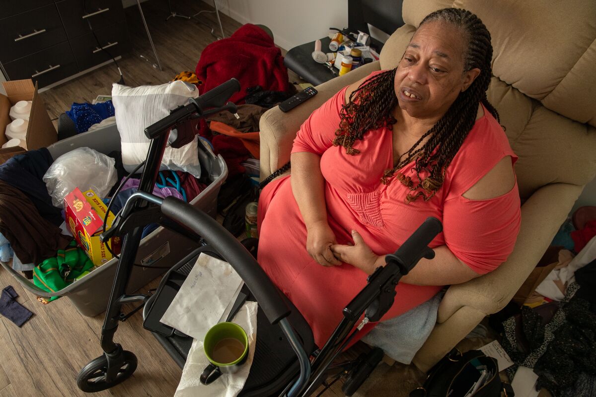 Yolanda Cunningham Smith sits in a chair with her walker in front of her. 