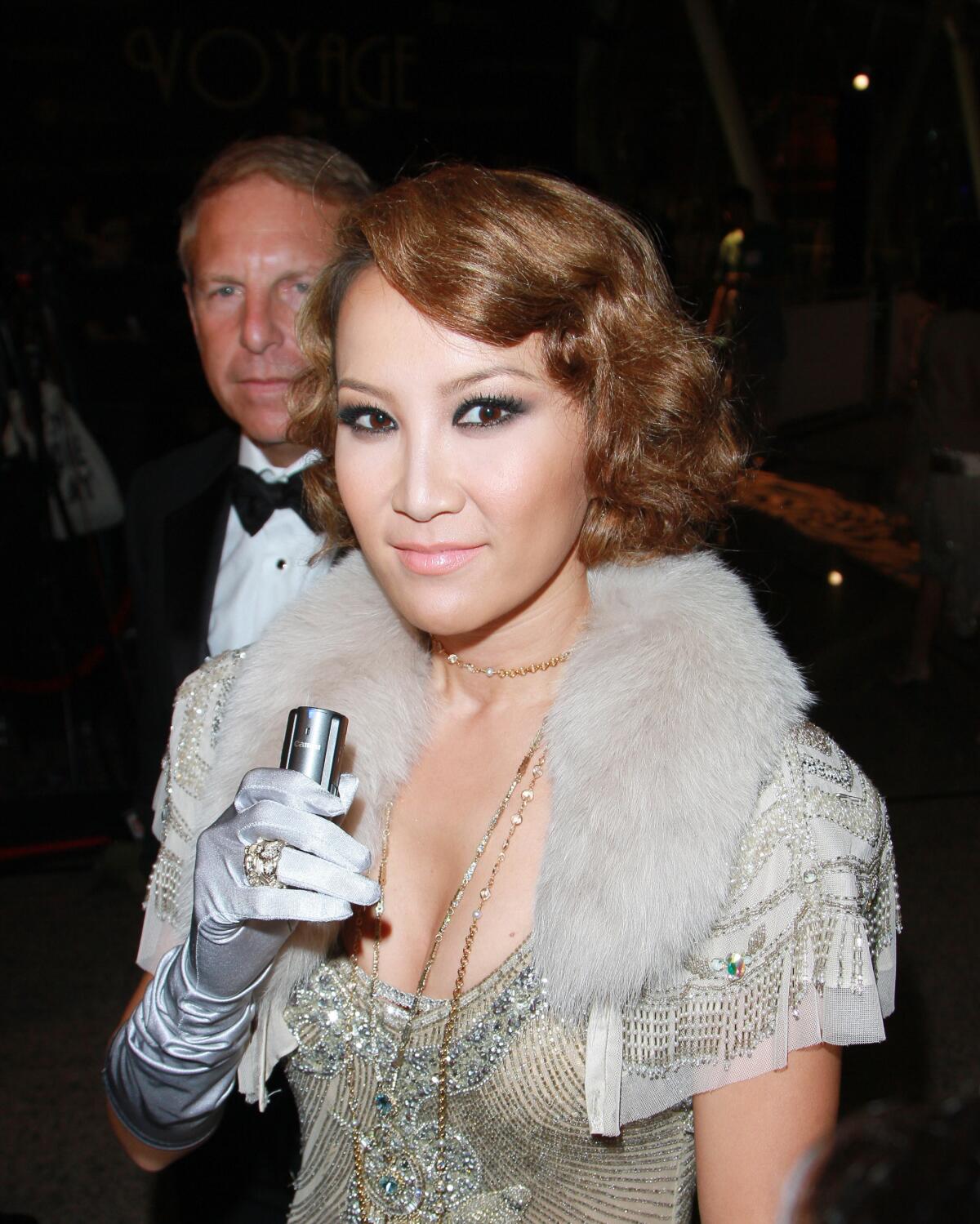 Coco Lee Man wears a silver and gold beaded dress with silver satin gloves. Husband Bruce Rockowitz wears a tuxedo.
