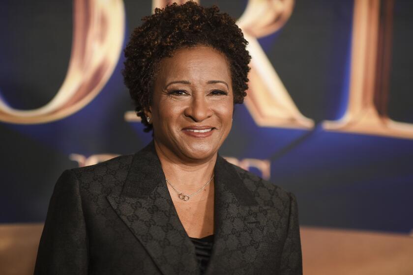 Wanda Sykes smiles in a black patterned suit.
