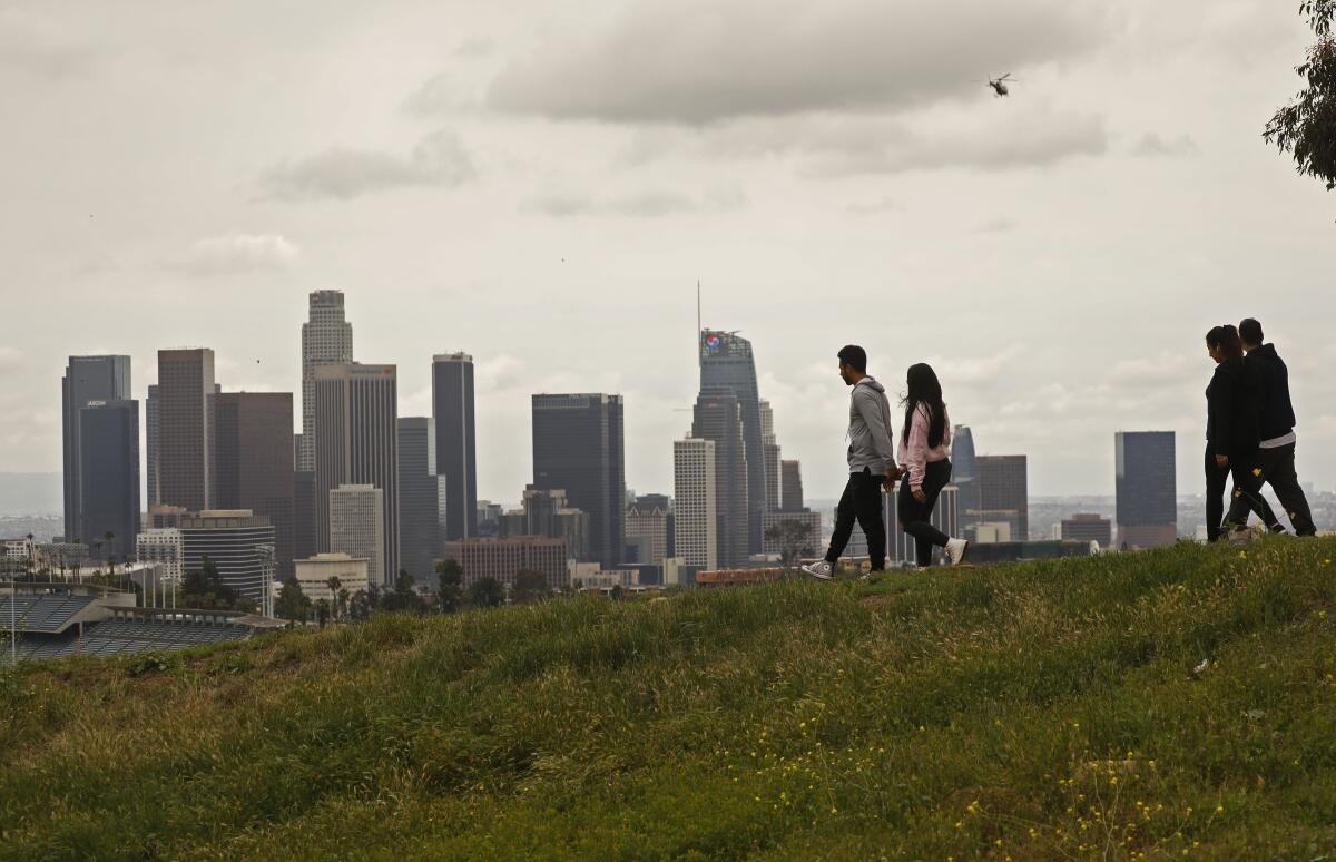 Two couples socially distance themselves while walking through Elysian Park on a cloudy Monday.