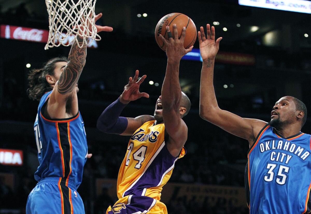 Lakers forward Kobe Bryant (24) drives to the basket against Thunder center Steven Adams, left, and forward Kevin Durant (35) in the first half.