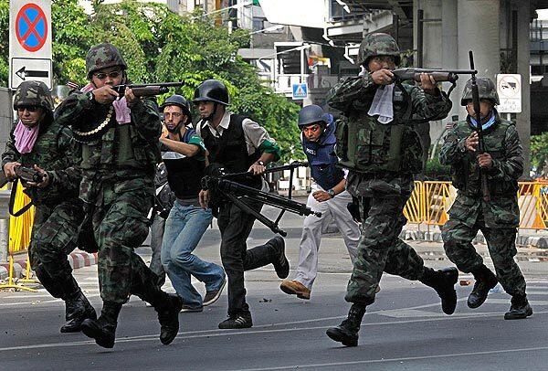 Thai soldiers race to take cover near a barricade put up by "Red Shirt" protesters.