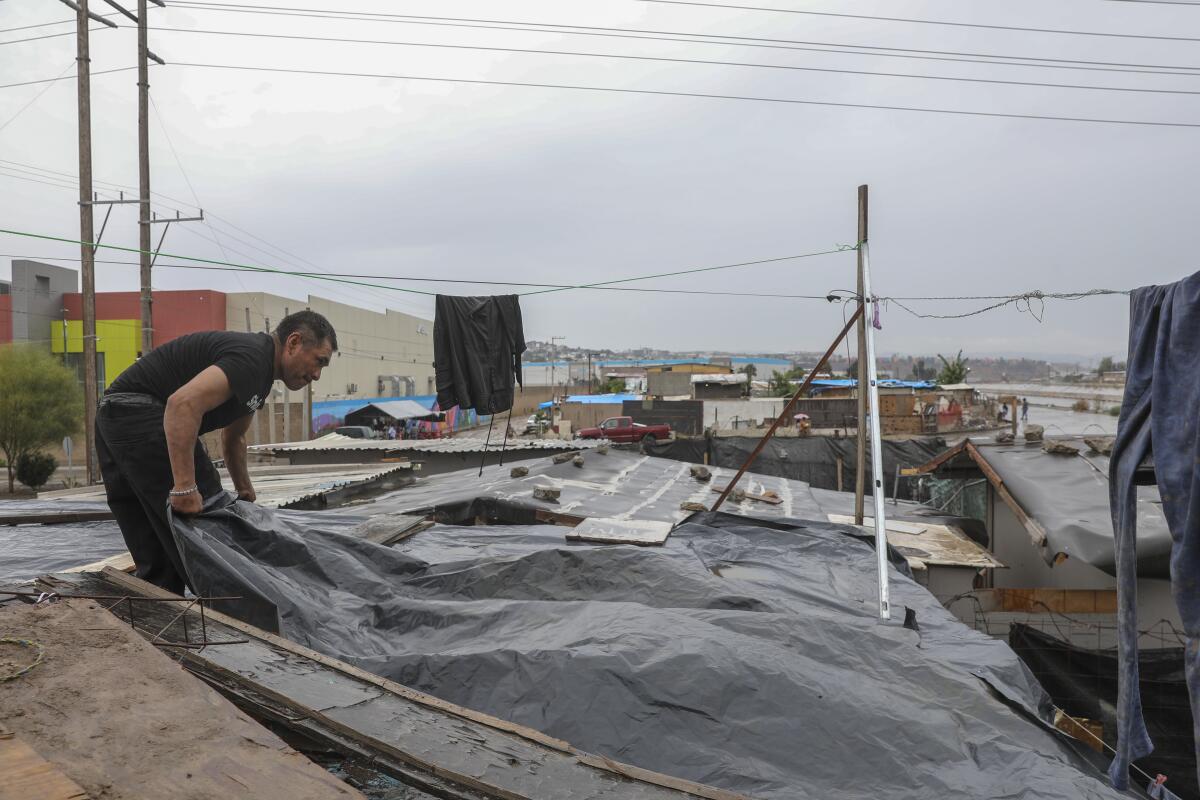 Miguel Ramirez lays a tarp over a home 