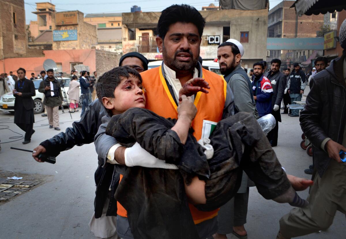 An injured child is carried away after an explosion at an auto repair shop in Peshawar, Pakistan.