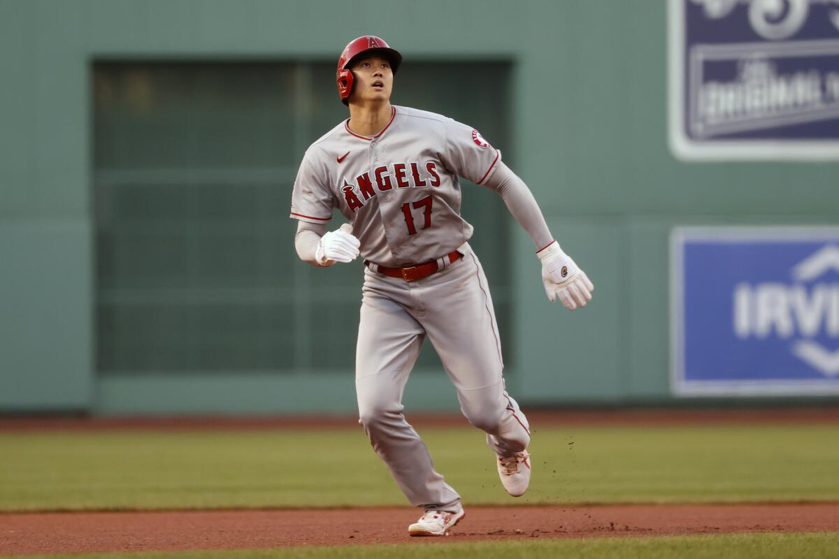 Shohei Ohtani tracks a ball hit in the air as he runs the basepaths.