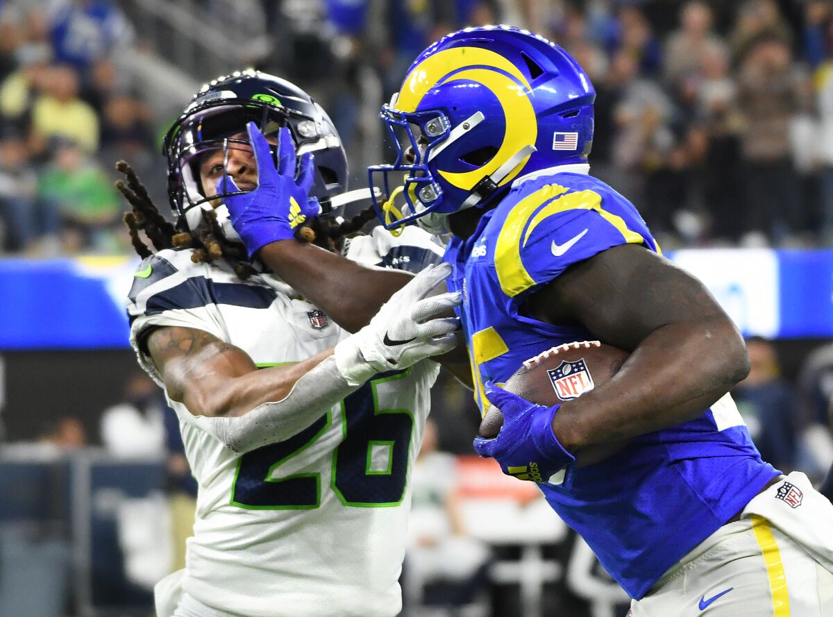 Rams running back Sony Michel stiff-arms Seahawks safety Ryan Neal.
