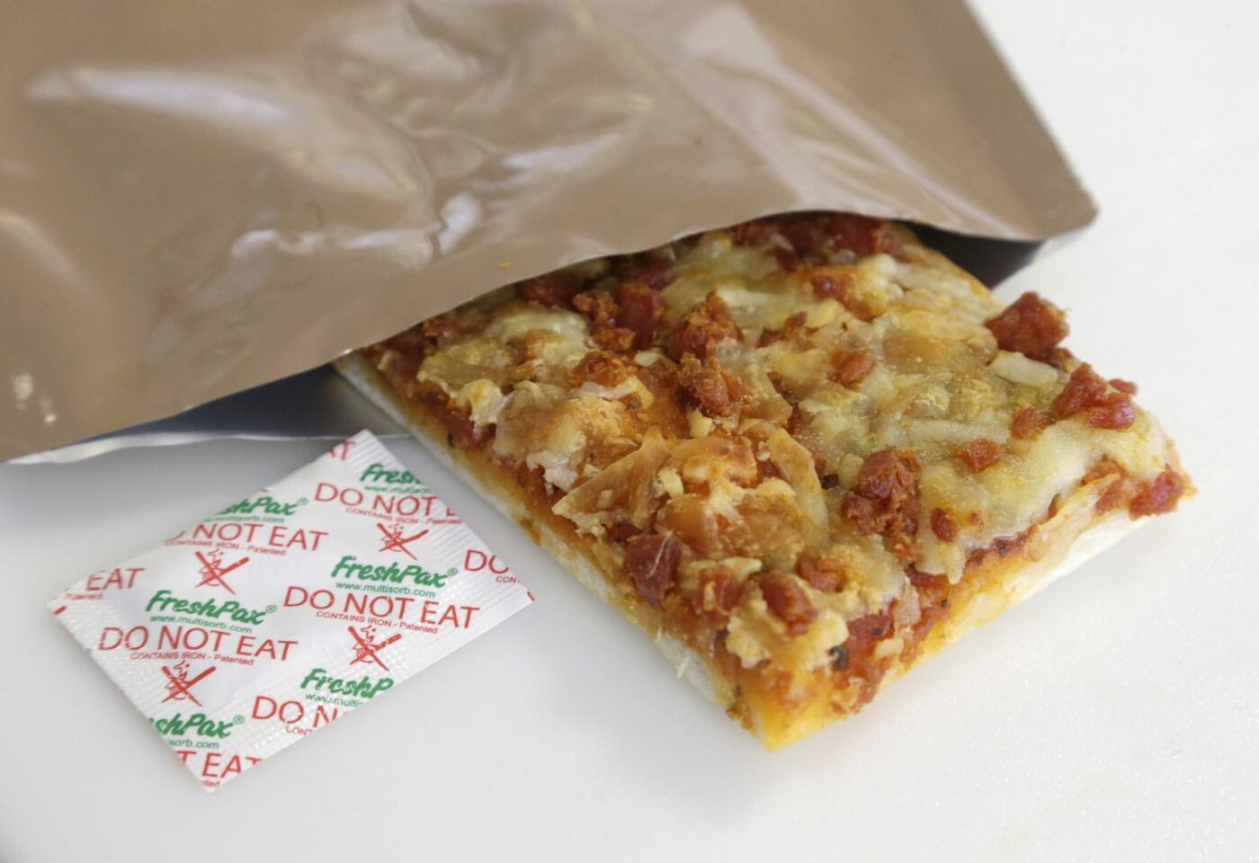 A slice of prototype pizza, in development to be used in military MREs (meals ready to eat), is shown in its packet with a smaller, freshness-keeping packet known as an oxygen scavenger. The pizza is being developed at the U.S. Army Natick Soldier Research, Development and Engineering Center in Natick, Mass.