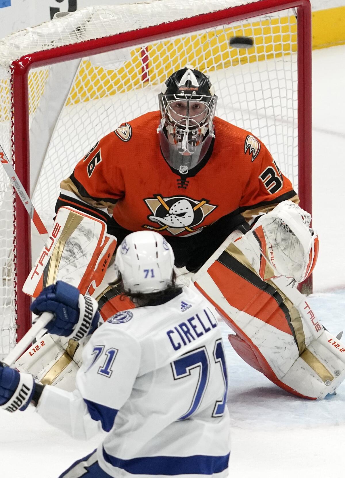 Ducks goalie John Gibson and Lightning center Anthony Cirelli watch the airborne puck in the first period Jan. 21, 2022.