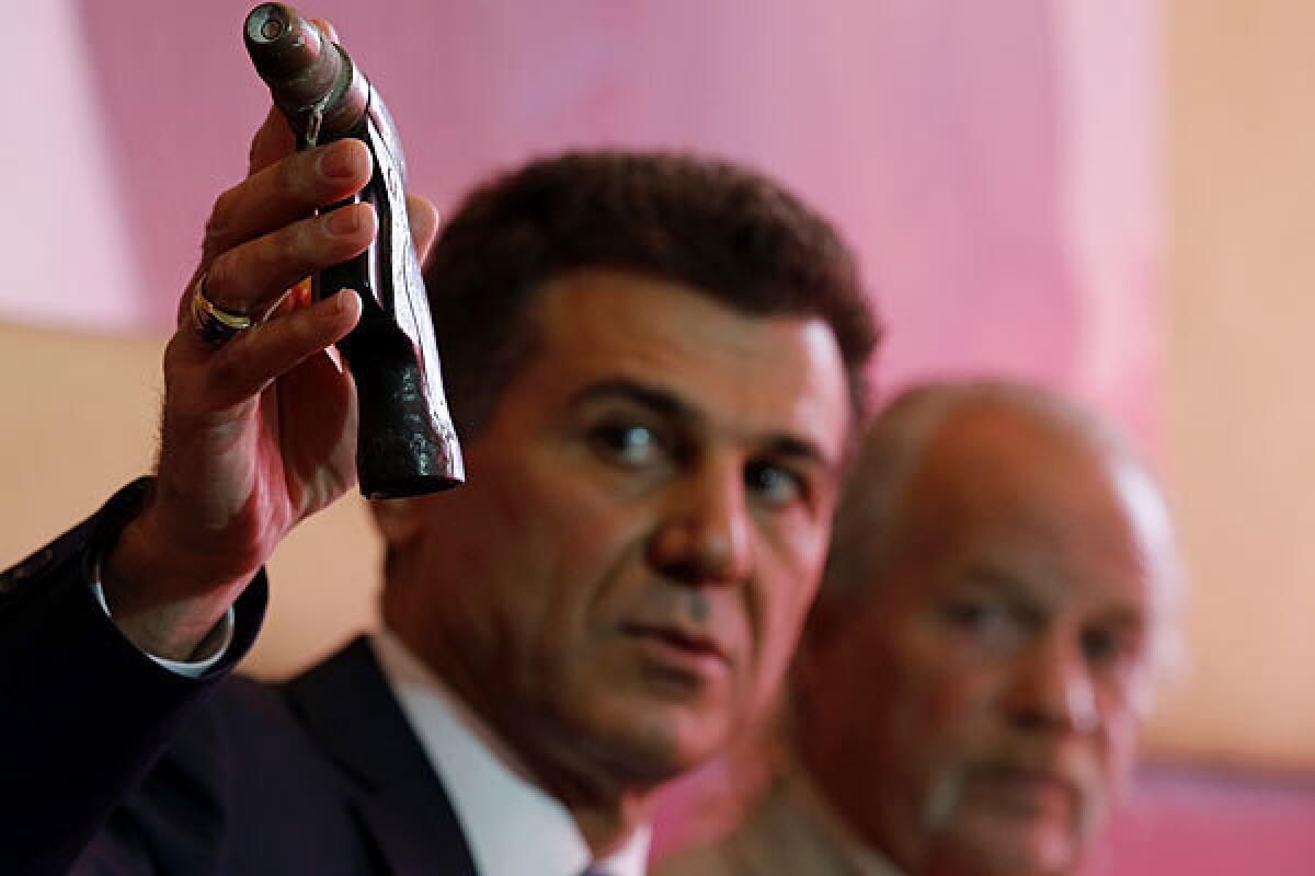 Attorney Garo Mardirossian last year holds up the water nozzle that Long Beach Police officers mistook for a gun when they shot and killed Doglas Zerby, 35, whose father, Mark Zerby, is at right.