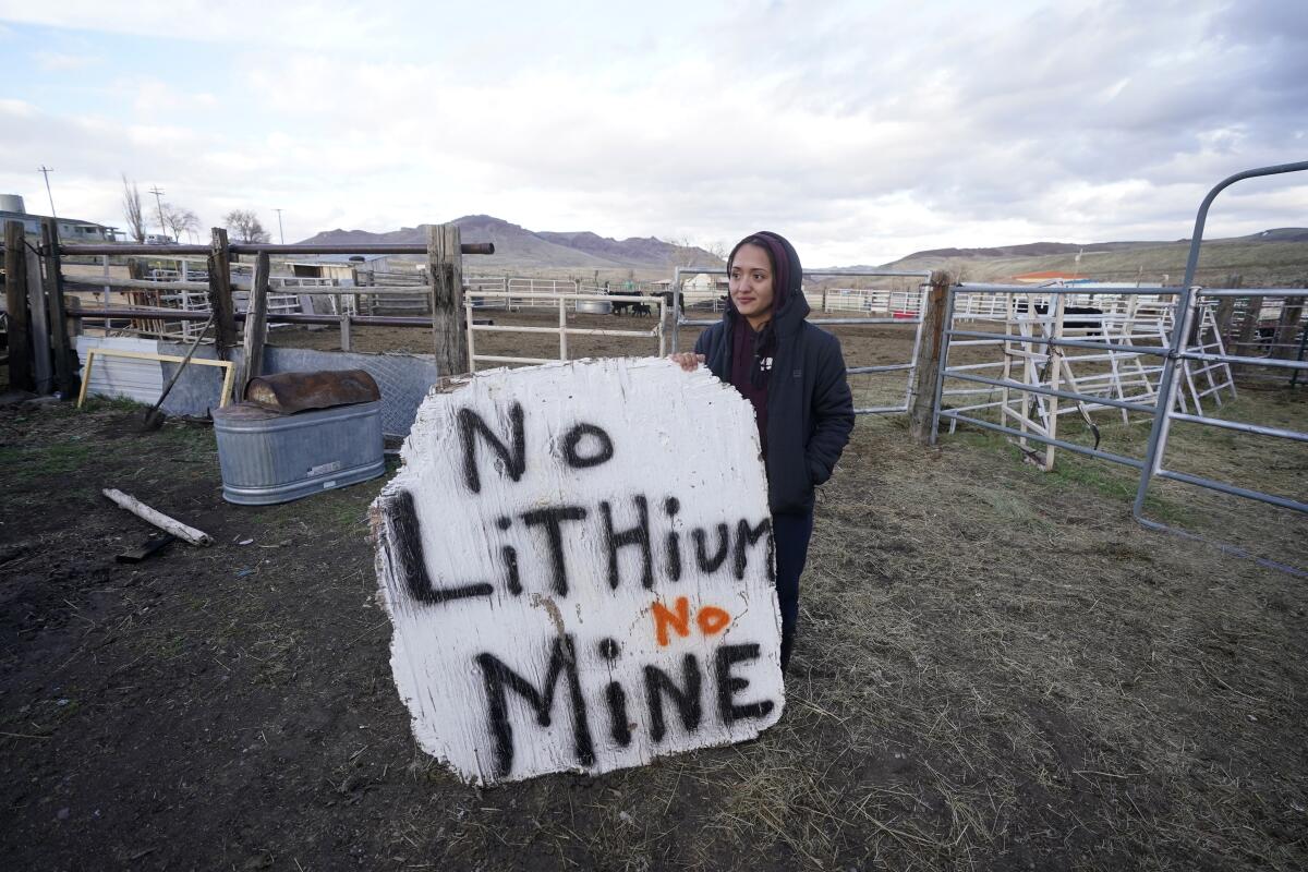 A woman holds a large hand-painted sign reading, "No Lithium No Mine," on the Fort McDermitt Indian Reservation in Nevada. 