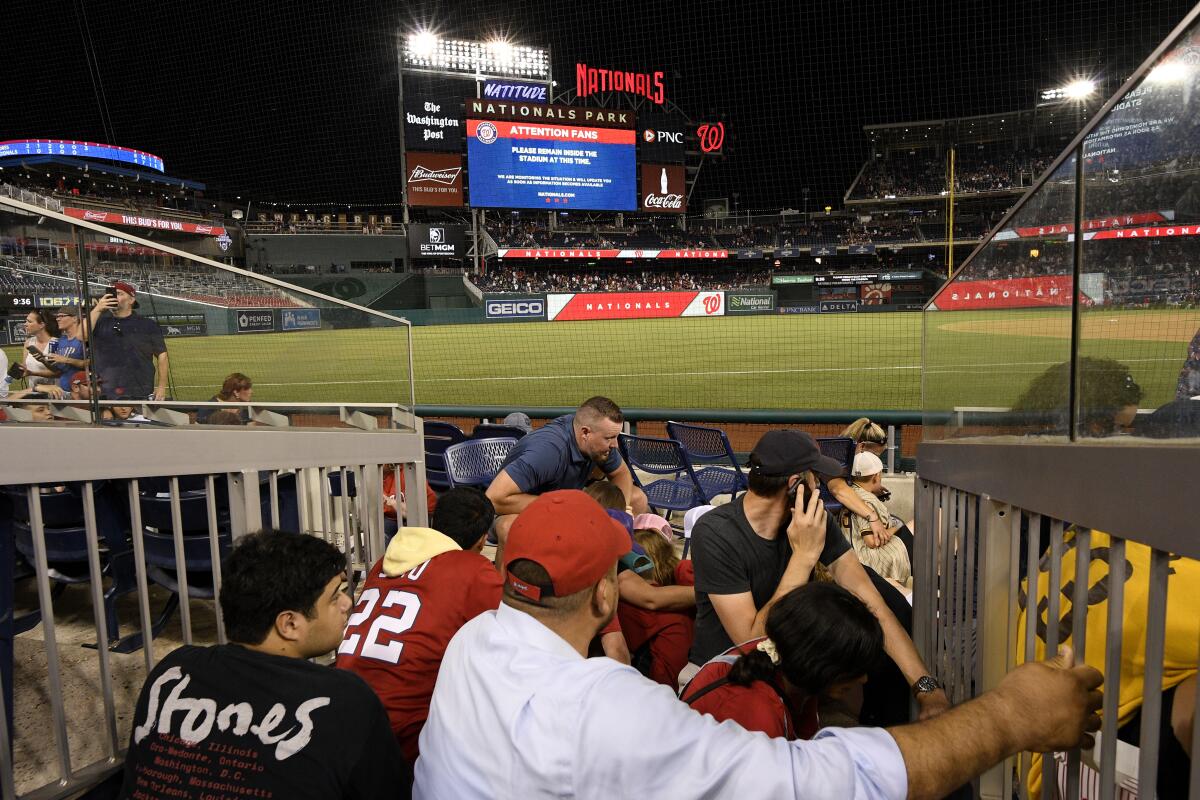 Aficionados buscan resguardo durante la pausa en el partido entre Padres y Nacionales d