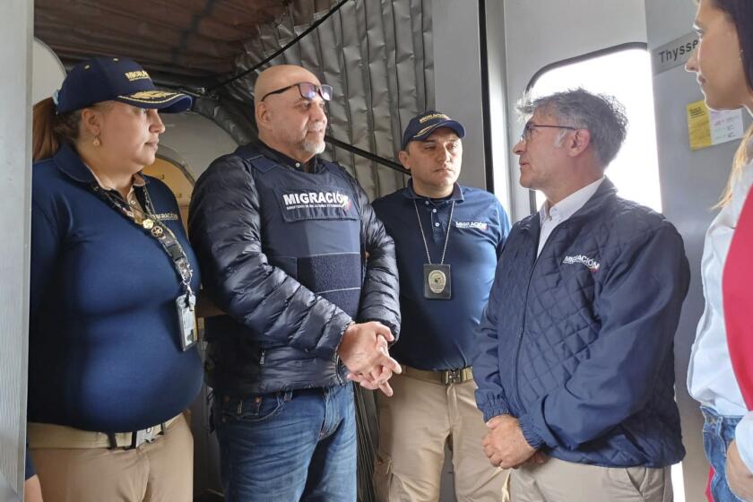 En esta foto difundido por Migración Colombia, funcionarios de migración reciben al líder exparamilitar Salvatore Mancuso en la puerta del avión a su llegada desde Estados Unidos, desde donde fue deportado tras cumplir condena por tráfico de drogas, en Bogotá, Colombia, el martes 27 de febrero de 2024. (Migración Colombia vía AP)