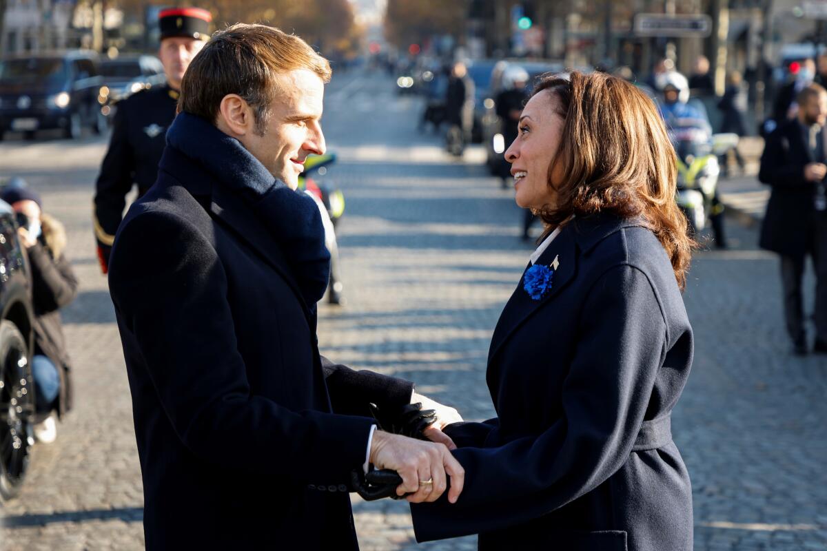 French President Emmanuel Macron and Vice President Kamala Harris clasp hands and exchange greetings