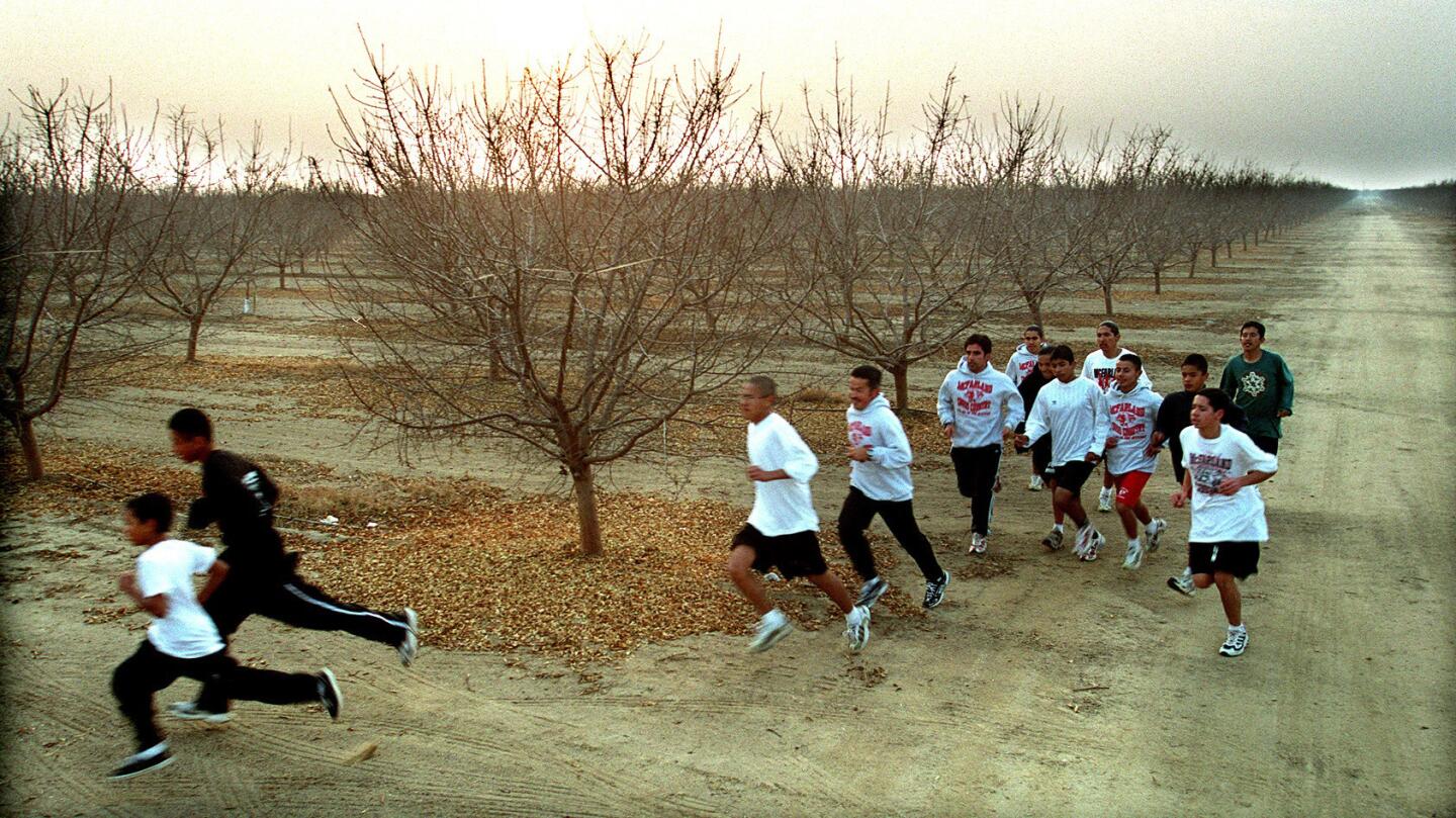 The boys of McFarland High School run through an almond orchard during practice at sunset in McFarland in 1999.