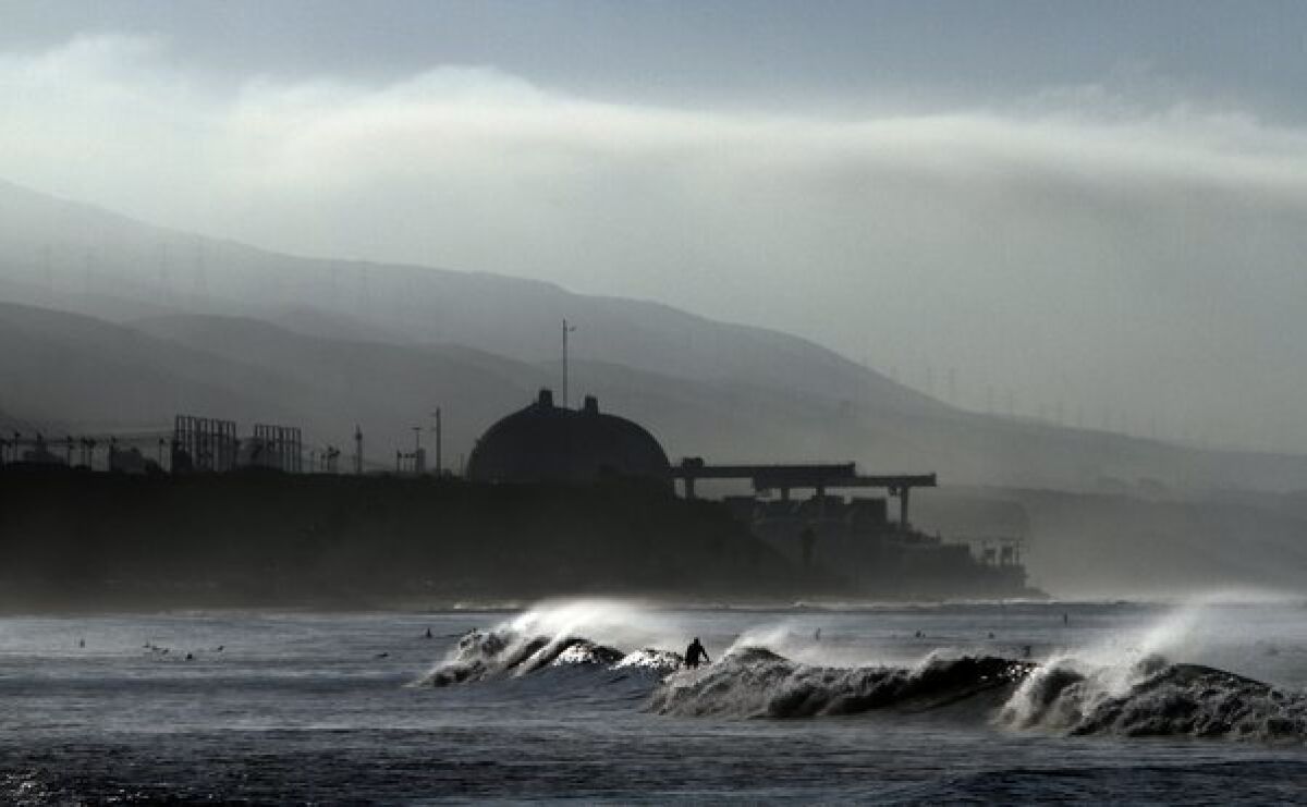 Surfers are out in the early morning with the San Onofre nuclear plant in the background.