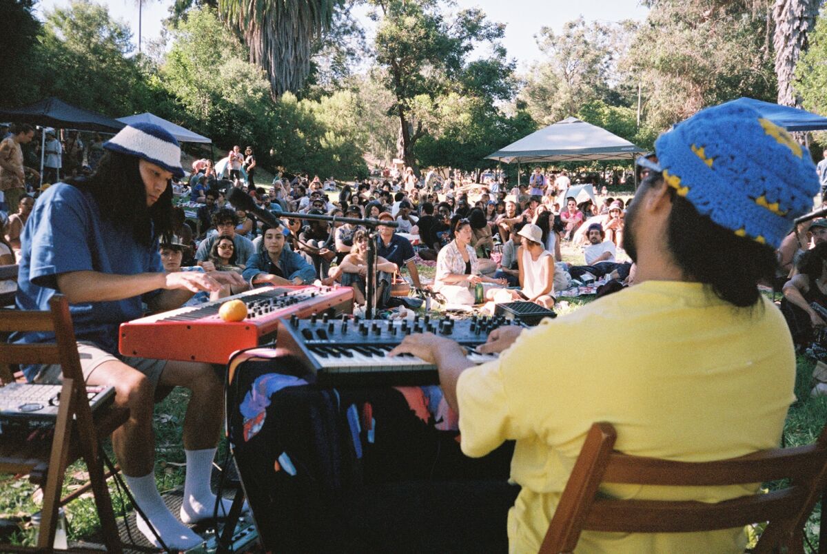 two people play music in front of a crowd outside 