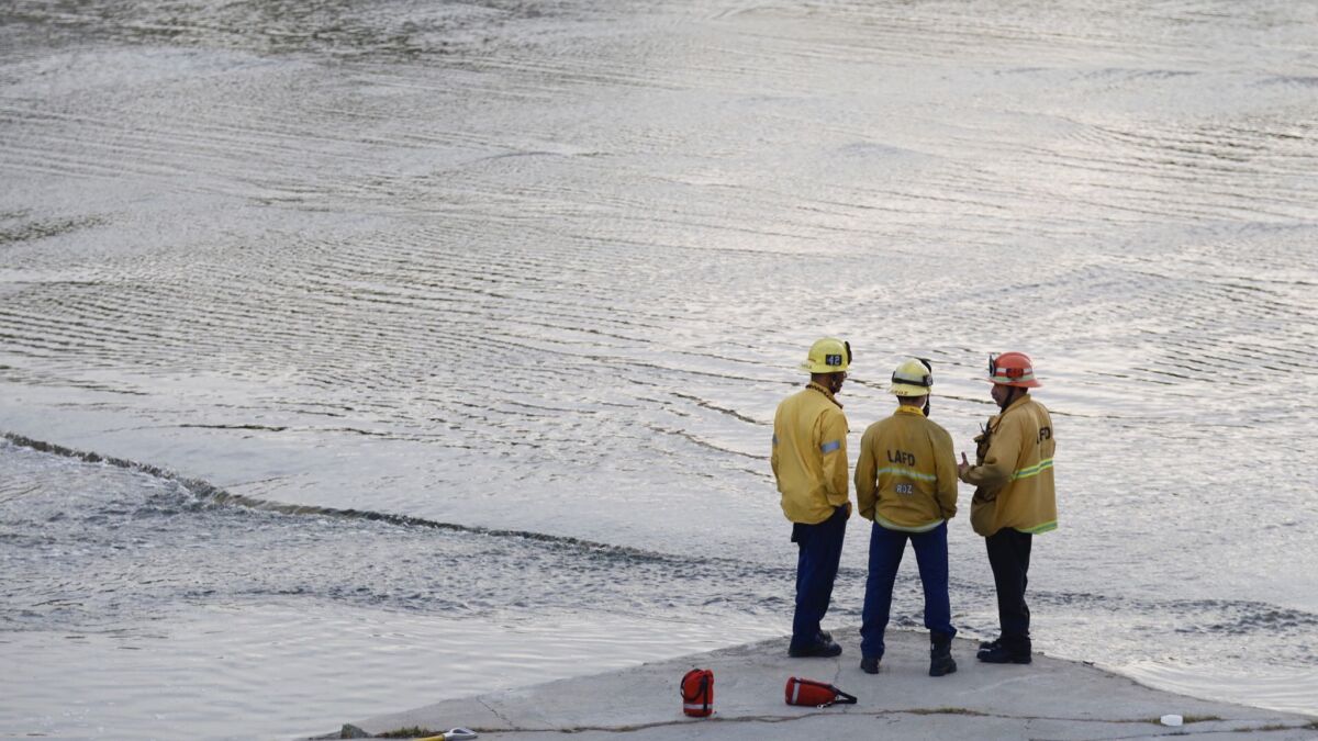 Firefighters confer on the search at the L.A. River near the 5 Freeway and Griffith Park.