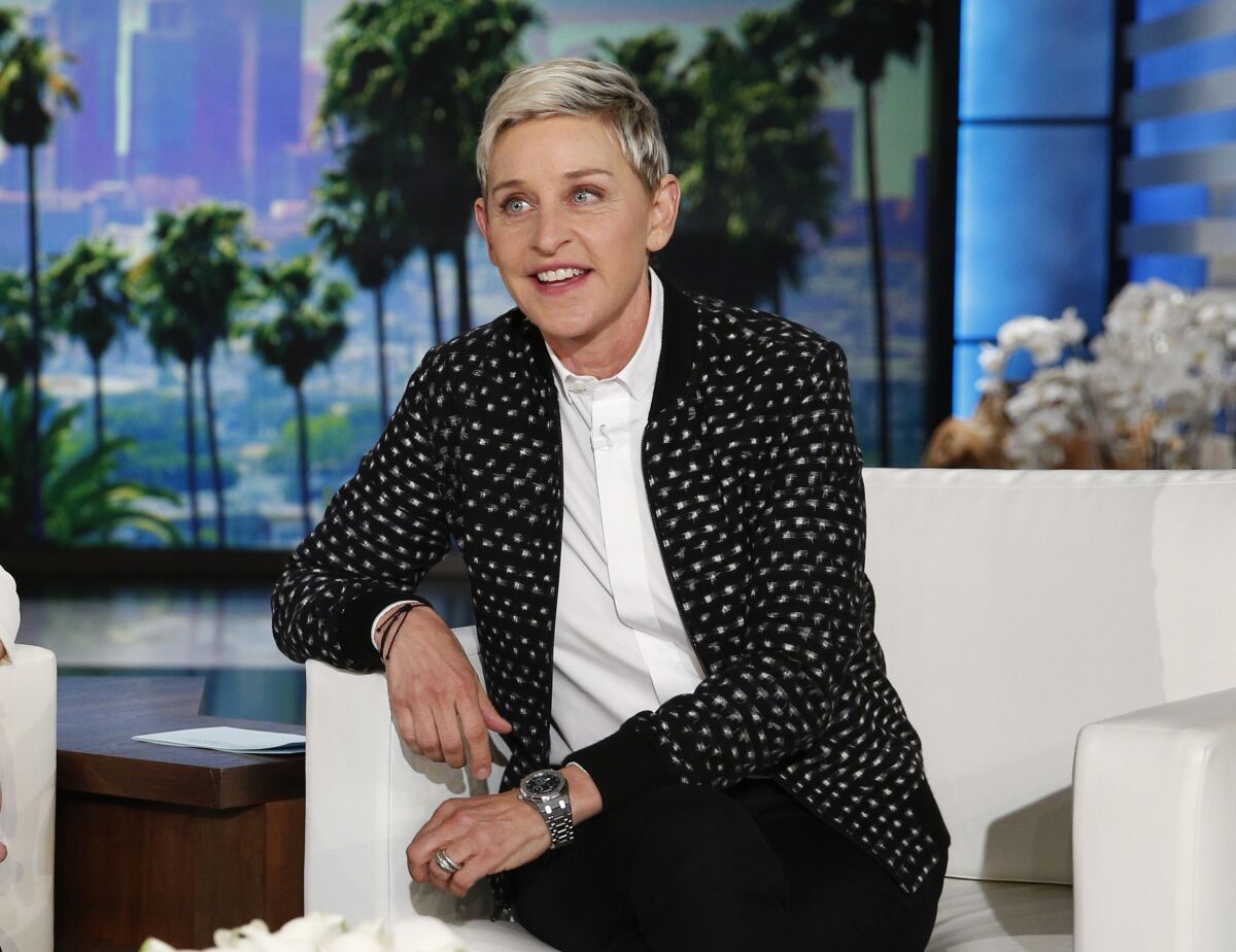 Ellen DeGeneres sits on a white chair.