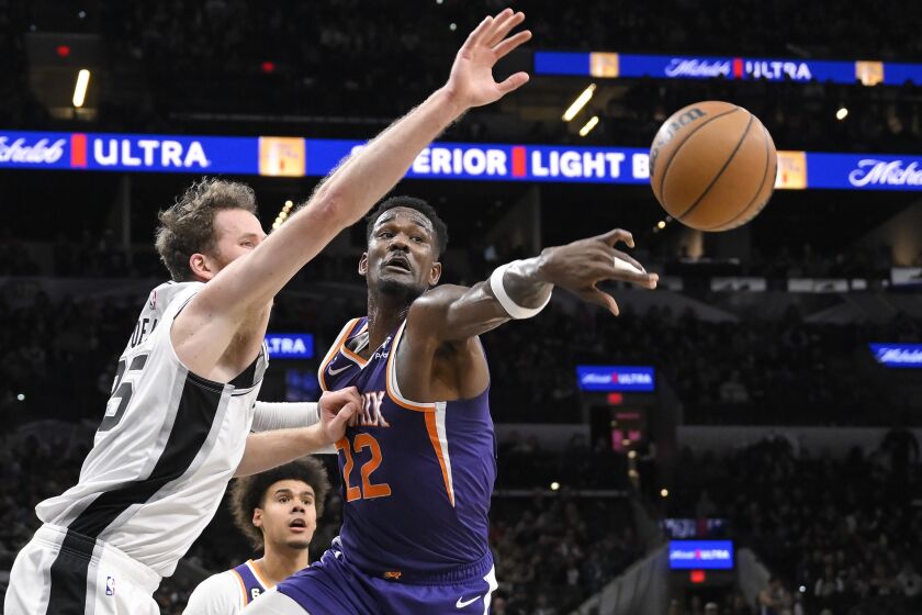 Phoenix Suns' Deandre Ayton (22) and San Antonio Spurs' Jakob Poeltl, left, grab for a rebound during the first half of an NBA basketball game, Saturday, Jan. 28, 2023, in San Antonio. (AP Photo/Darren Abate)