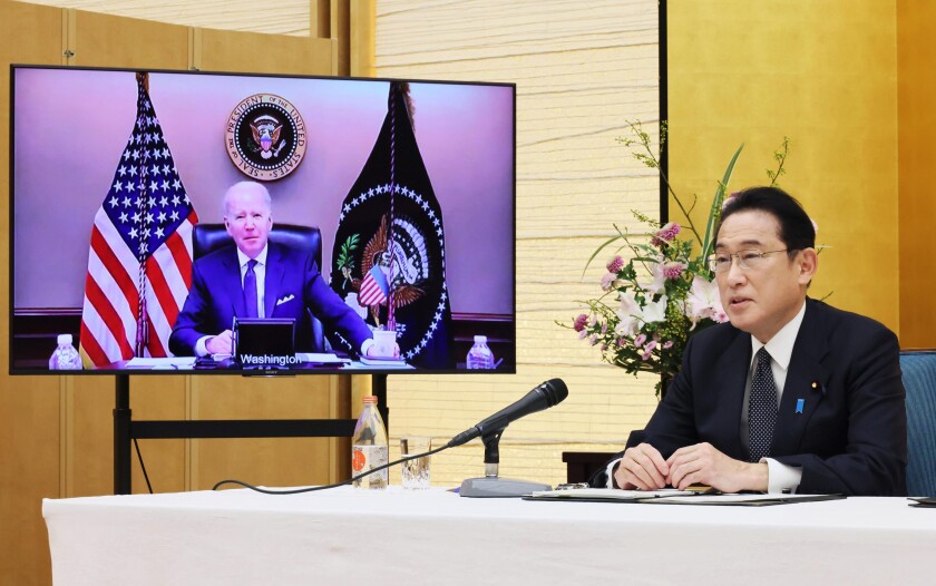 Japanese Prime Minister Fumio Kishida, right, sitting in a room of the prime minister's official residence in Tokyo, Friday, Jan. 21, 2022, talks in a virtual meeting with U.S. President Joe Biden, shown in the monitor. Biden and Kishida on Friday used their first formal meeting to discuss concerns about China's growing military assertiveness that's spurring increasing disquiet in the Pacific. (Cabinet Secretariat/Kyodo News via AP)