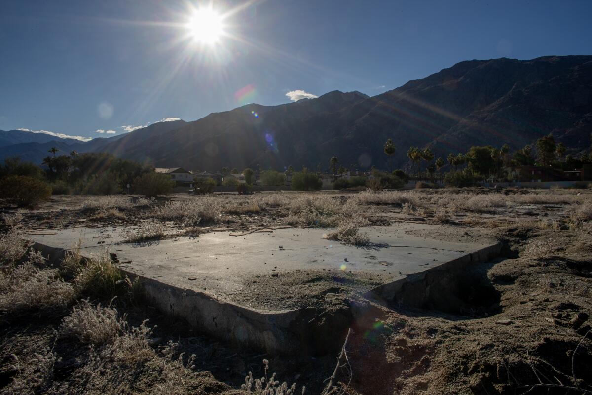 A concrete slab in the dirt below a sunny sky and mountains.