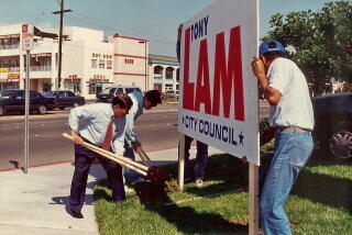 People put up a campaign sign for Tony Lam