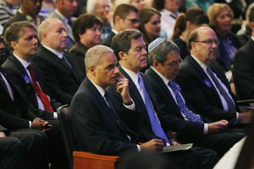 Atty. Gen. Eric H. Holder Jr., seated next to Kansas Gov. Sam Brownback, attends a service at the Jewish Community Center in Overland Park, Kan.