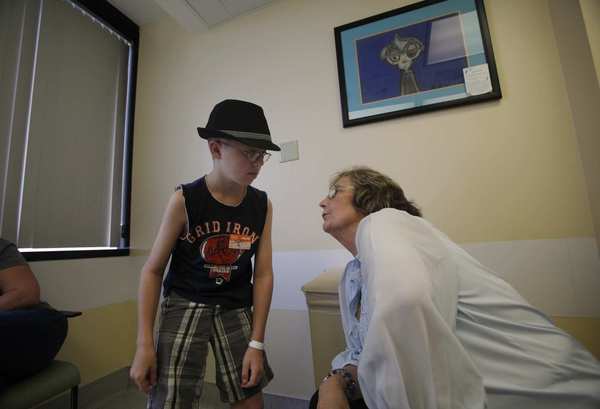Barbara Britt, right, a nursing care manager at Children's Hospital Los Angeles, listens to 12-year-old Jordan Johnson explain how he is tolerating radiation.