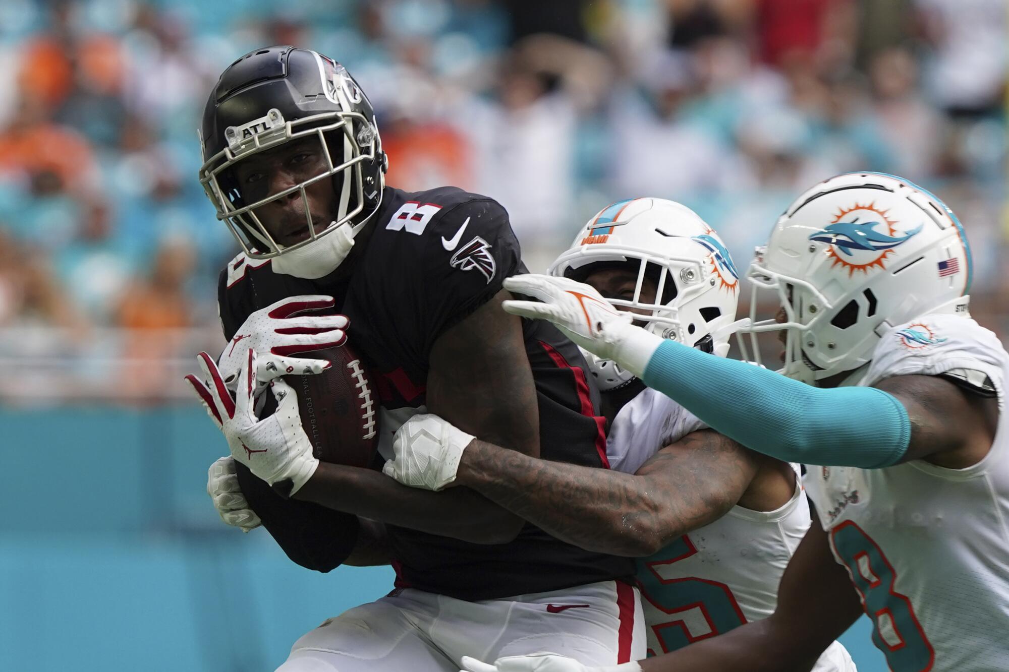 Atlanta Falcons tight end Kyle Pitts makes a catch while defended by Miami Dolphins defenders.