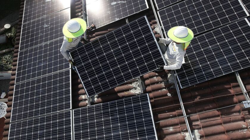 Workers install a solar panel system on the roof of a home in Florida in January.