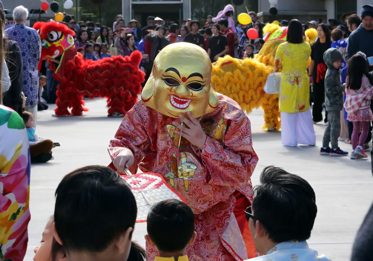 A masked performer entertains as the lion dance is performed by the Shengai Dance group during a Lunar New Year Festival.