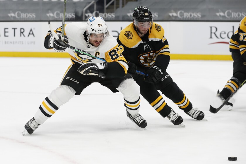 Pittsburgh Penguins' Sidney Crosby and Boston Bruins' Zach Senyshyn eye the puck during the second period of an NHL hockey game Thursday, April 1, 2021, in Boston. (AP Photo/Winslow Townson)