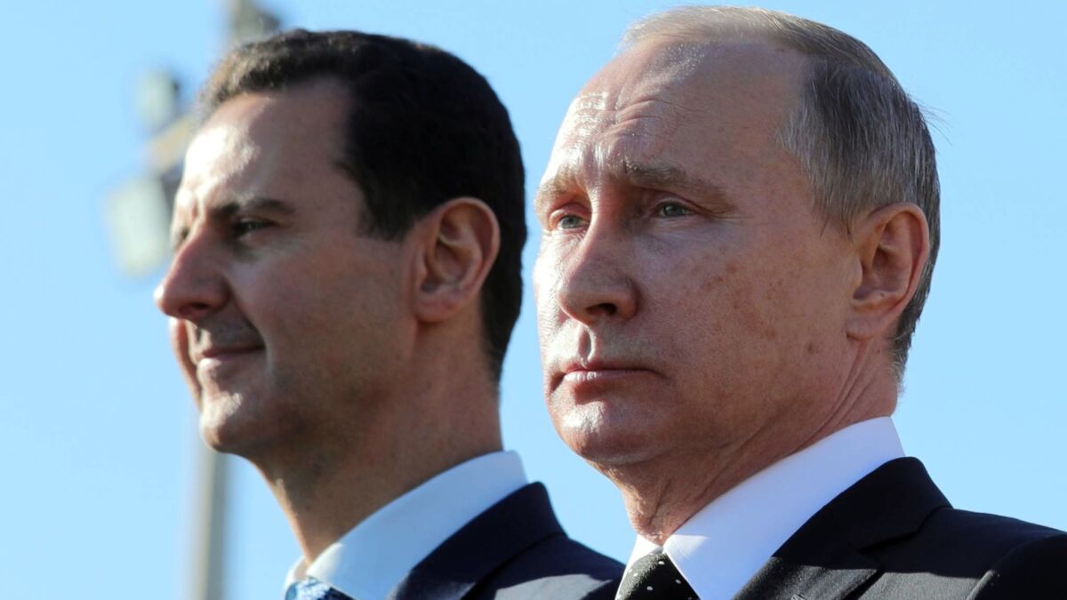 Syrian leader Bashar Assad, left, and Russian President Vladimir Putin watch troops march in Syria on Dec. 11, 2017.
