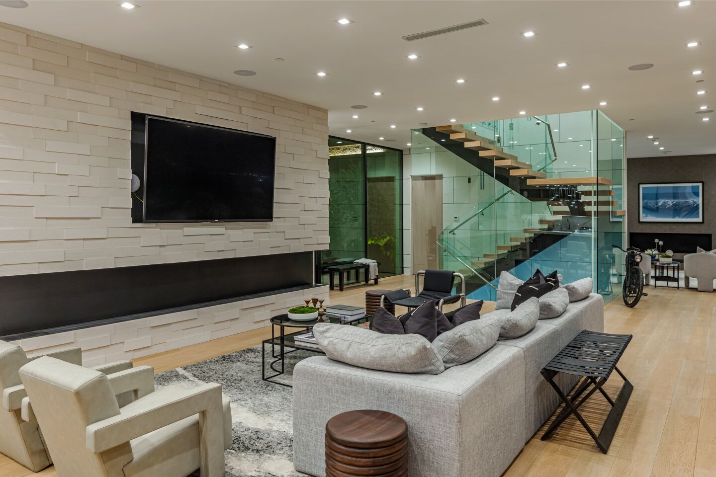 The living room has a built-in TV, furniture, a floating stairway and track lighting.