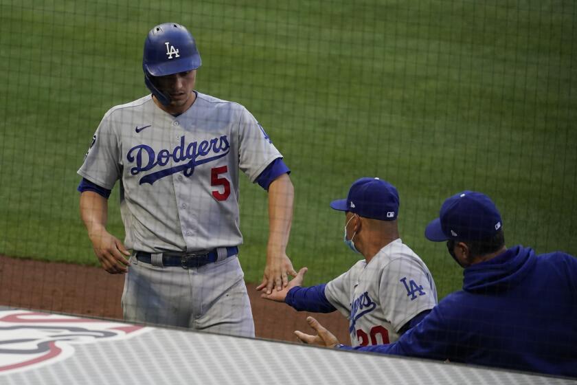 The Dodgers' Corey Seager gets a high-five from manager Dave Roberts after scoring in the fourth inning May 8, 2021.