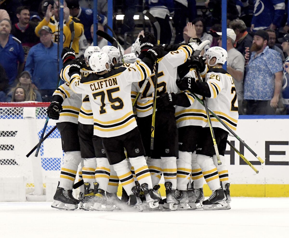 Boston Bruins celebrate center Charlie Coyle's (13) game winning overtime goal during an NHL hockey game against the Tampa Bay Lightning Friday, April 8, 2022, in Tampa, Fla. (AP Photo/Jason Behnken)