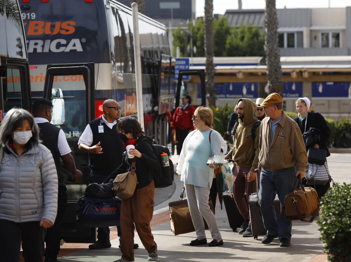  Train passengers walk from an Amtrak train to buses at the Oceanside Transit Center.
