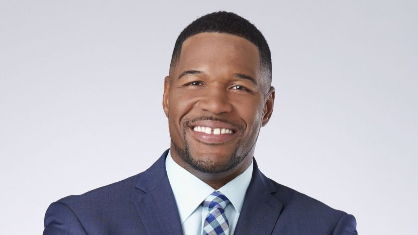 A portrait of Michael Strahan in a blue jacket and checked tie.