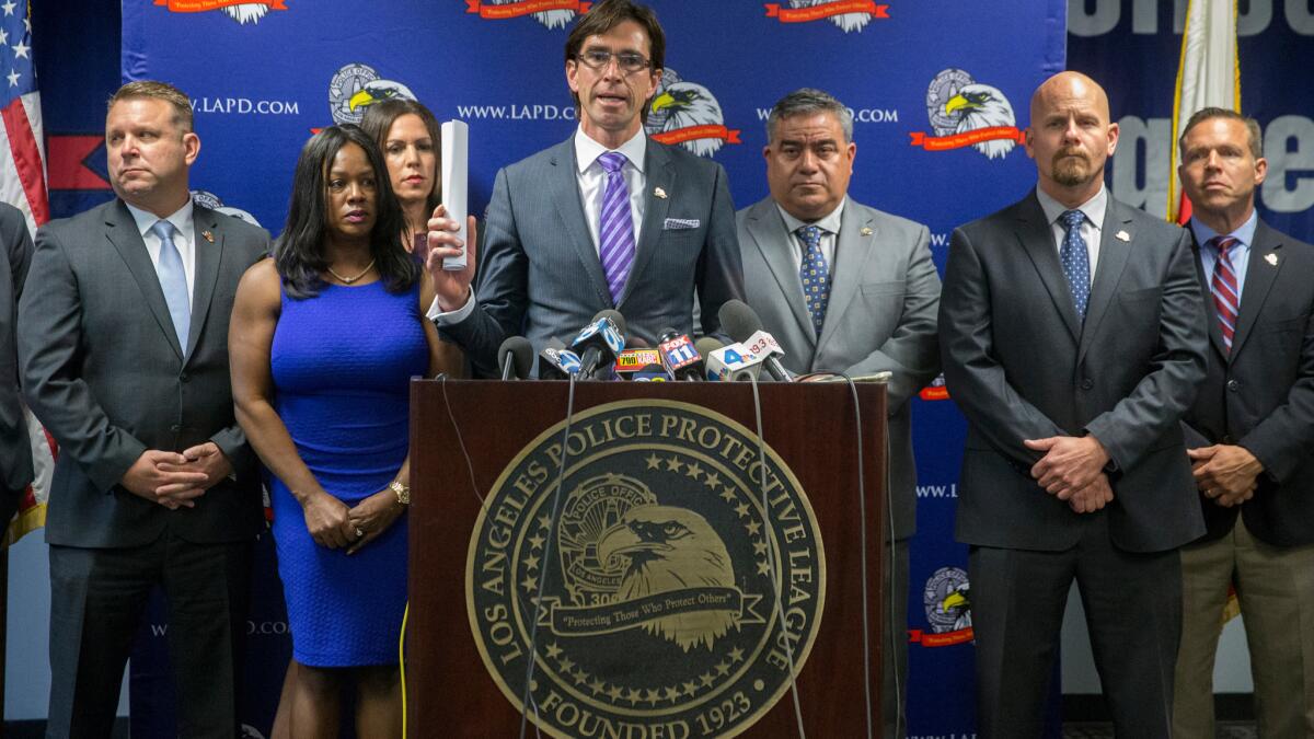 An attorney is surrounded by officials with the Los Angeles Police Protective League, the union that represents the rank and file officers of the LAPD, at a news conference held to announce a lawsuit against the city and police chief on May 19.