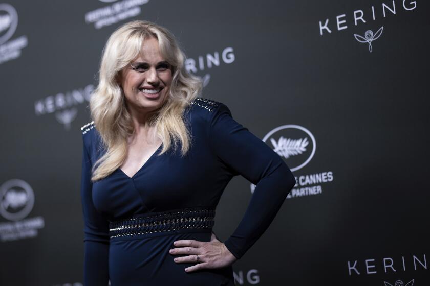 Rebel Wilson posed in blue dress smiling away from the camera. 