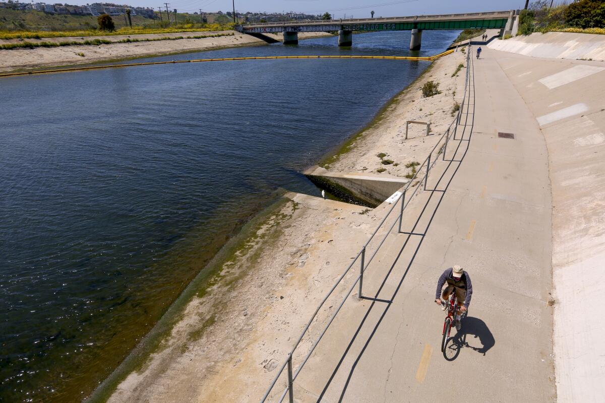 A lone bicyclist rides alongside water on the Ballona Creek bike path in Marina Del Rey.