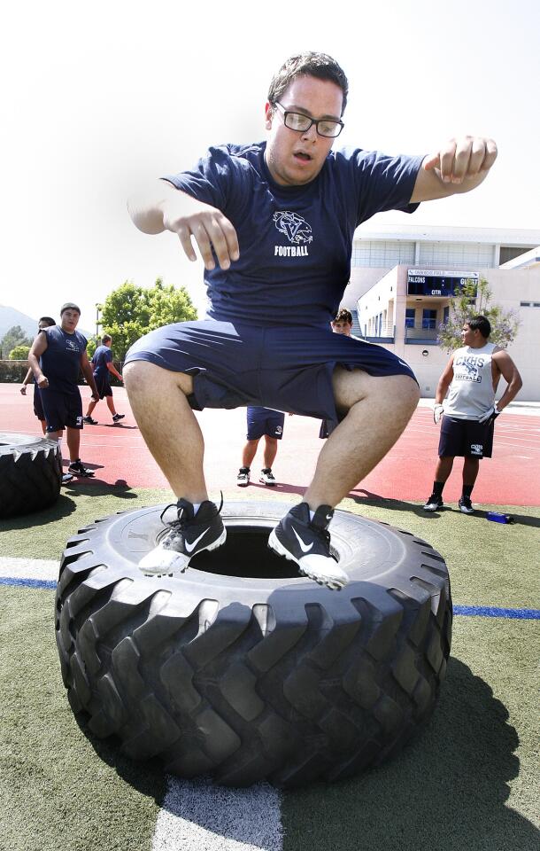 Arin Boghoz, 16, after flipping the tire, jumps in and out of it, one of many strength training drills for the 2012 Crescenta Valley football season in La Crescenta.