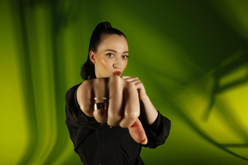 Kat Dennings, star of "Dollface" on Hulu, extends a fist toward the camera.