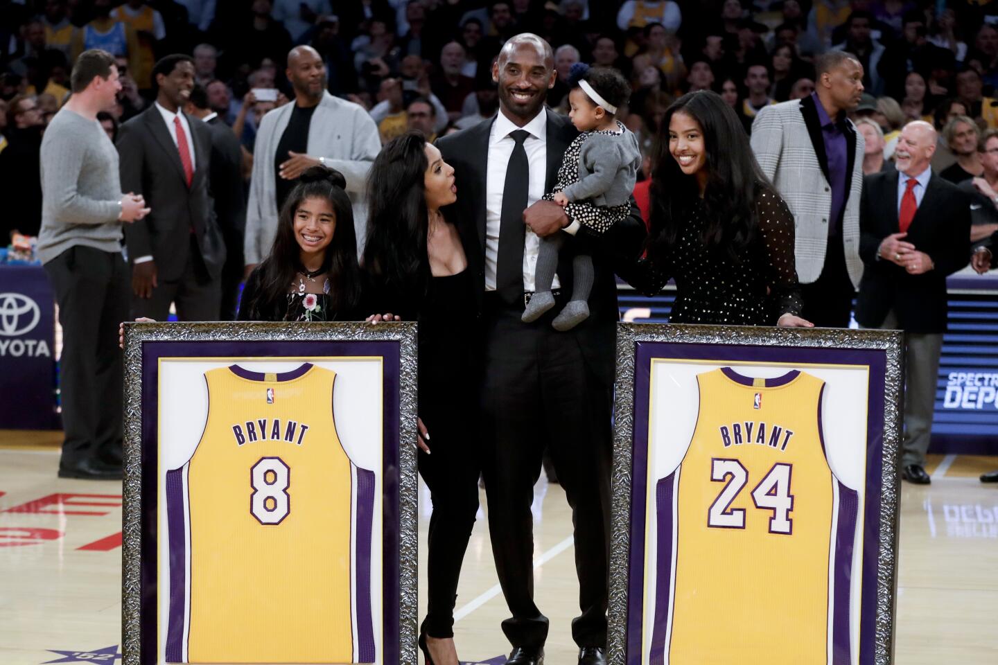 Gianna, Vanessa, Kobe (holding baby Capri) and Natalia Bryant on the court with his two framed retired jerseys.