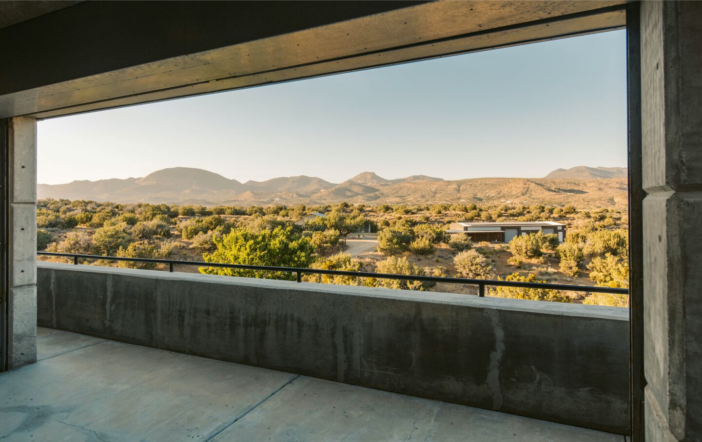 Desert hills and mountains are seen from a concrete balcony.