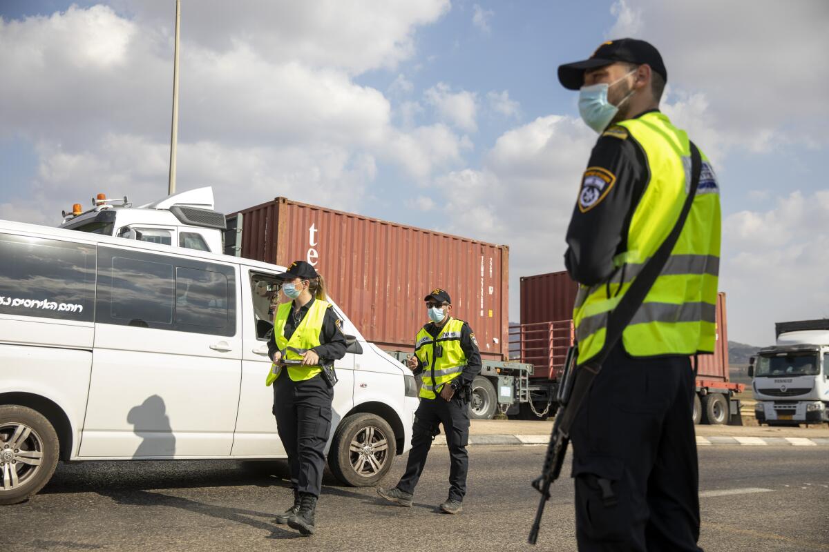 Three people in uniform watch a van.