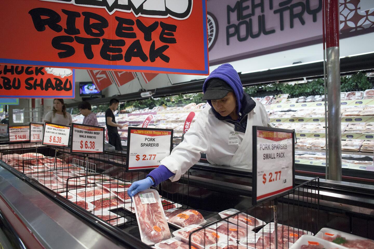A worker organizes and restocks packs of pork spare ribs in the meat and poultry section at the new Tokyo Central store in Costa Mesa on Thursday, July 23.