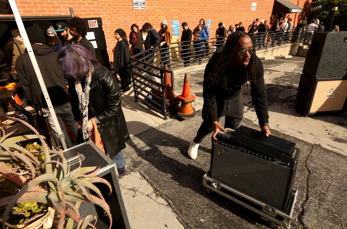 Musicians wheel out amplifiers and other equipment at a rehearsal complex.