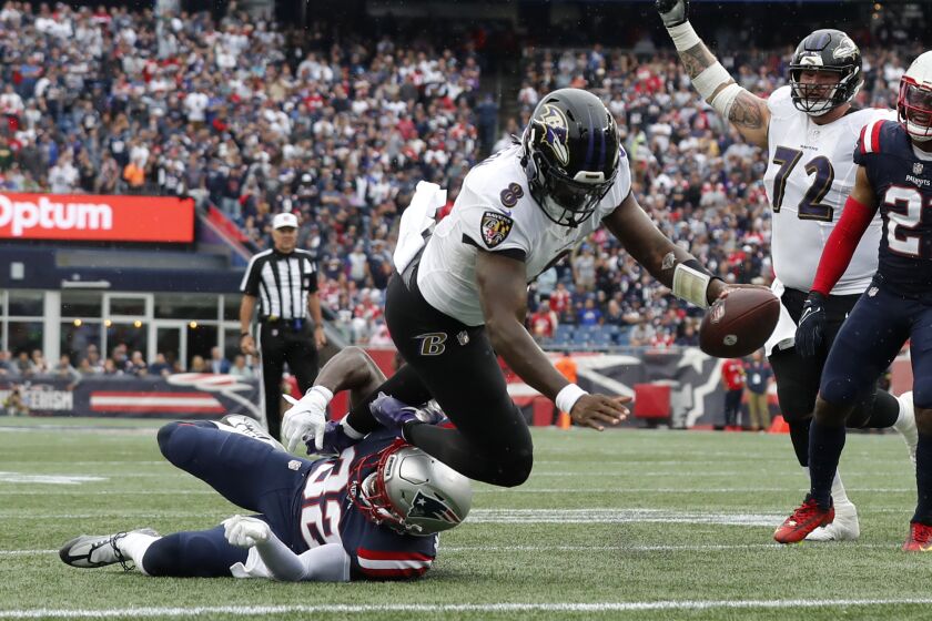 Baltimore Ravens quarterback Lamar Jackson (8) scores a touchdown as New England Patriots safety Devin McCourty (32), below left, tries to defend in the second half of an NFL football game, Sunday, Sept. 25, 2022, in Foxborough, Mass. (AP Photo/Michael Dwyer)